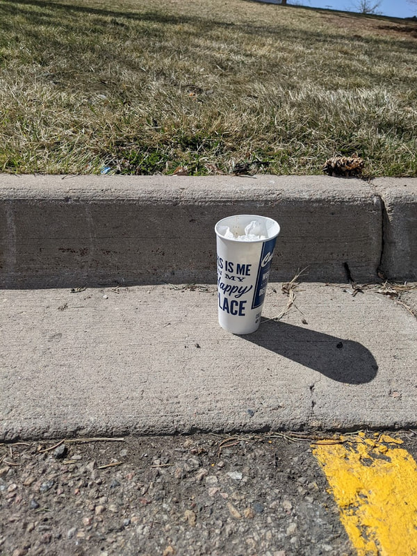 Abandoned paper cup and trash in parking lot